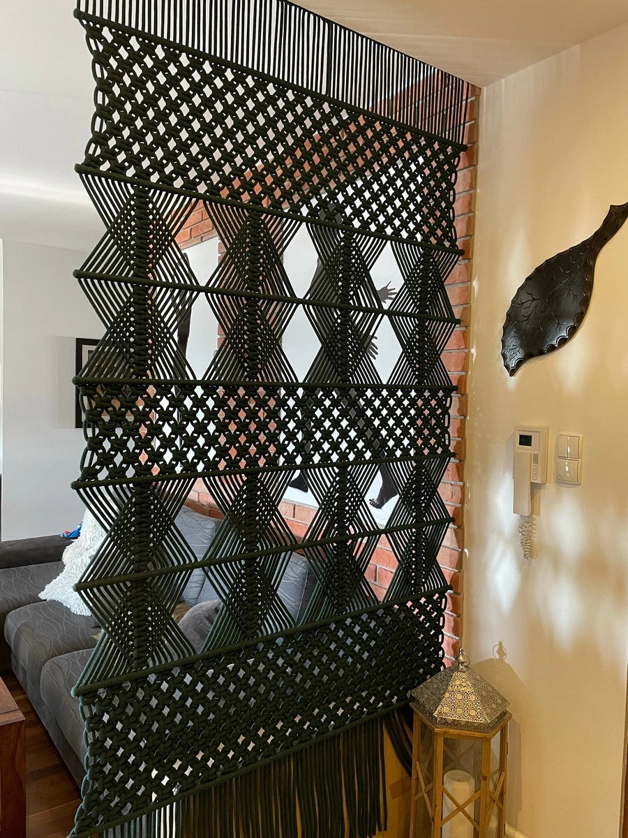 Duża, ręcznie wykonana makrama SKADI w nowoczesnym wydaniu i butelkowej zieleni, pełniąca funkcję ścianki działowej. Projekt NORDART podkreśla geometryczną estetykę i nowoczesny charakter wnętrza, wprowadzając wyraźny, elegancki akcent.