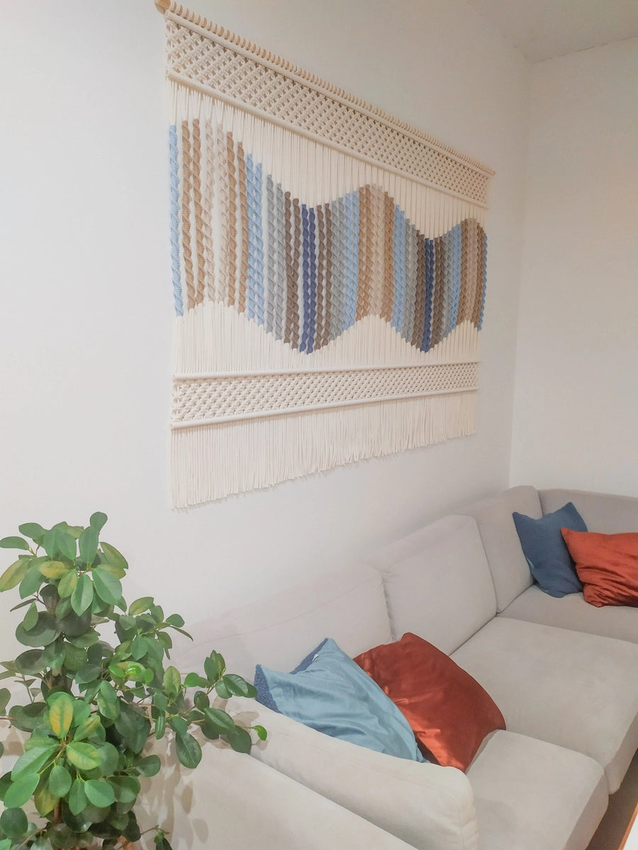 Elegancka niebieska makrama jako dekoracja ścienna w przytulnym salonie. Ręcznie wykonana ozdoba w głębokim odcieniu niebieskiego stanowi wyrazisty, a zarazem harmonijny akcent w nowoczesnym wnętrzu.