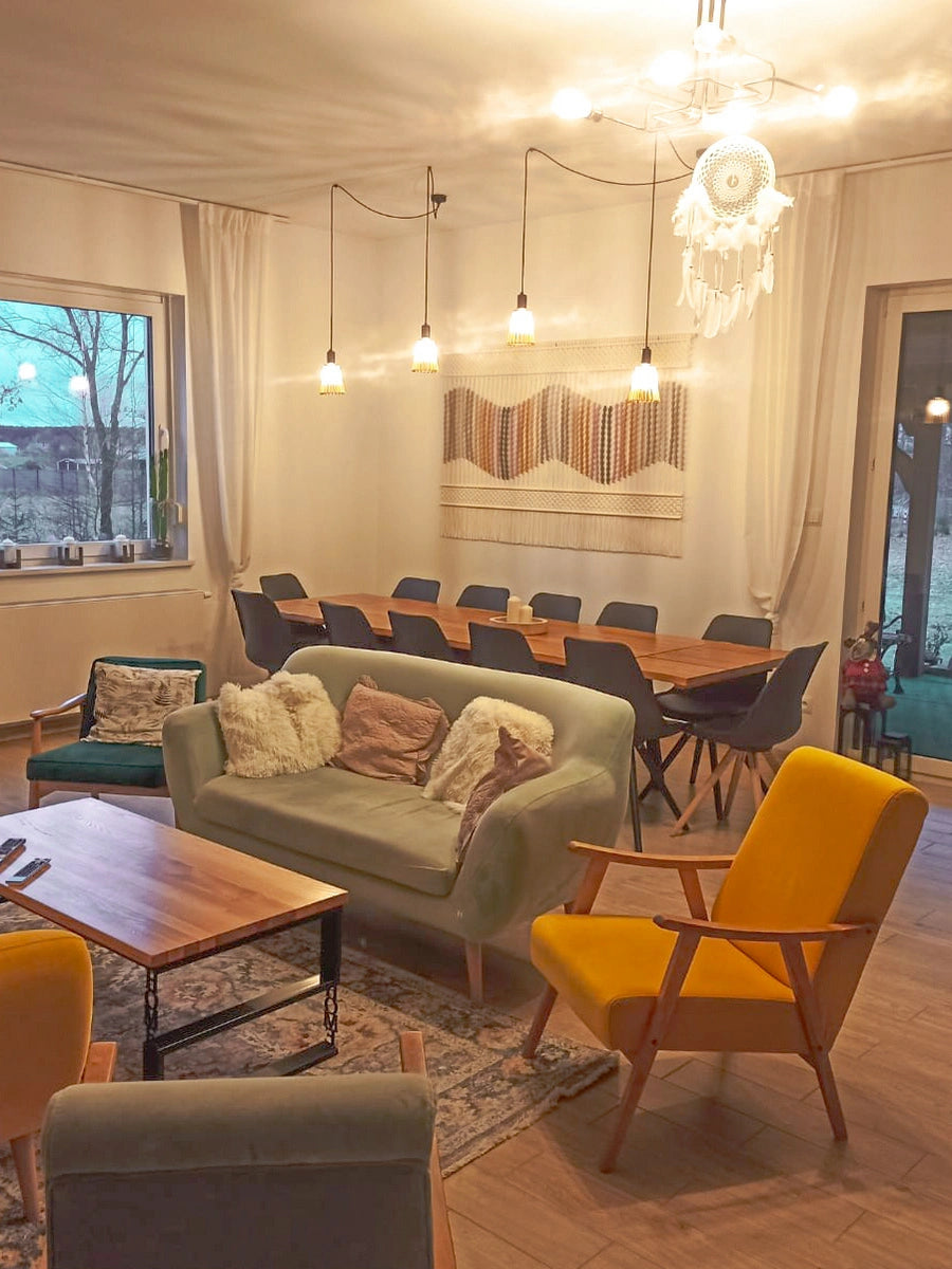 Duża makrama ścienna NORDART „Seaside Dunes” w kolorze ecru z falistym wzorem w odcieniach beżu, zieleni, różu i musztardowym, dekoracja na ścianę do salonu z jadalnią zawieszona nad stołem.